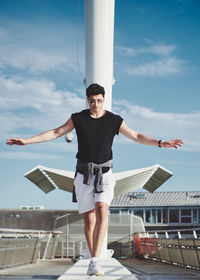 Full length of man with arms raised against blue sky