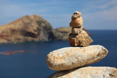 Close-up of stack of rocks by sea against sky