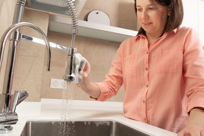 Young woman washing hands in sink