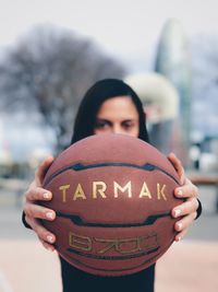 Close-up of woman holding ball against sky in city