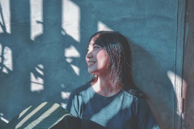 Portrait of beautiful young woman against wall