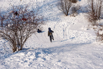 Child running down a snow track, while having fun in the park.