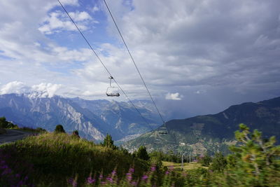 Overhead cable car over mountains against sky