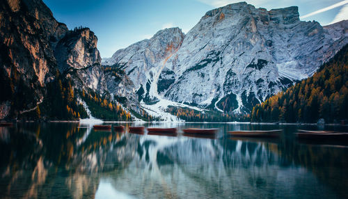 Boats in lake against snowcapped mountains