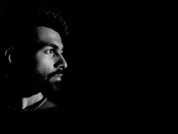 Close-up of thoughtful man looking away against black background