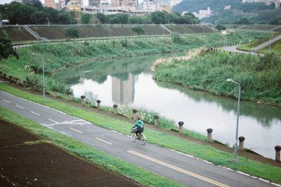 People riding bicycle on road by lake