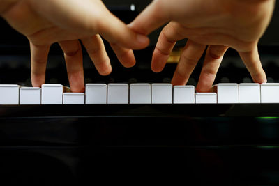 Cropped hands of woman playing piano