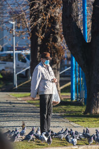 Rear view of man standing by tree trunk in park