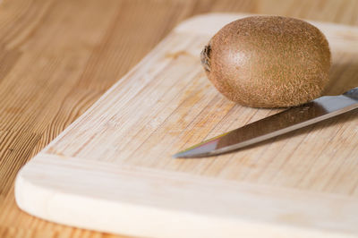 Close-up of kiwi and knife with cutting board on wooden table