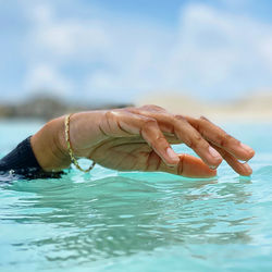 Cropped hand of man swimming in sea