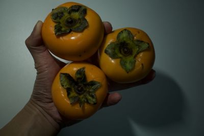 Close-up of hand holding fruit against white background