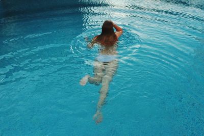 Rear view of woman swimming in pool