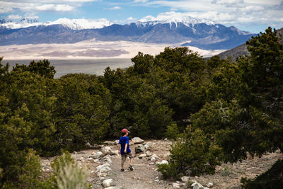 Rear view of boy walking on mountain against sky