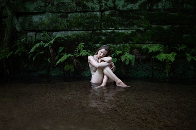 Full length of woman sitting by plants