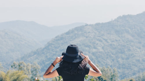 Rear view of man standing on mountain against sky