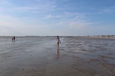 People walking on beach against sky