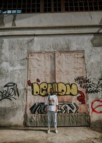 Full length of man standing against graffiti wall