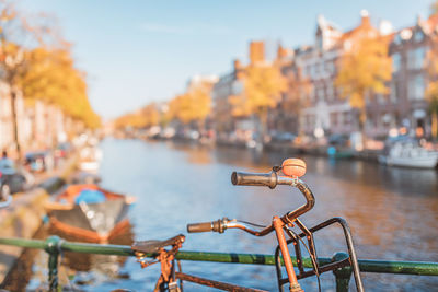 Close-up of bicycle by canal and buildings