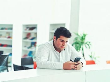 Man using mobile phone while sitting at table