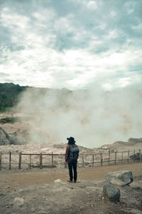 Rear view of man standing on mountain against sky