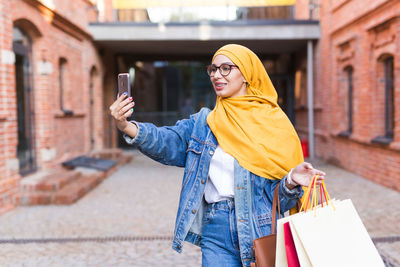 Midsection of woman holding smart phone in city