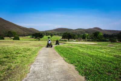 People riding motorcycle on road against sky