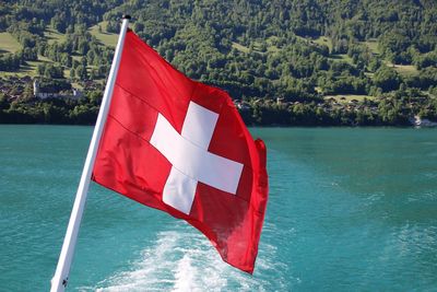 Red flag on boat in sea against mountain swiss