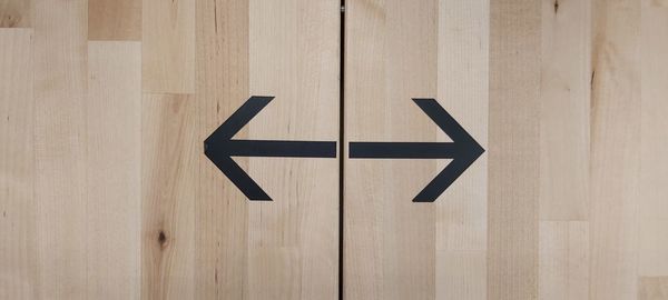 Close-up of arrow sign on wooden wall