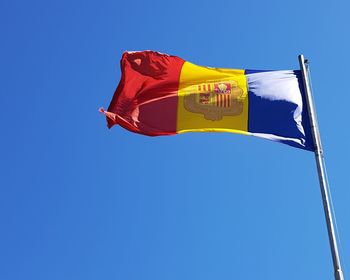Low angle view of flag against clear blue sky