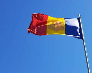 Low angle view of andorran flag against clear blue sky