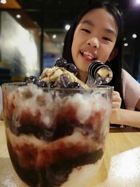 Portrait of smiling girl with ice cream sitting at restaurant