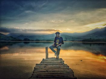 Man standing on pier over lake against sky