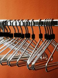 Close-up of empty coathangers hanging on rack against wall