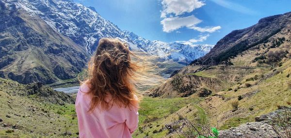 Rear view of woman looking at mountains against sky