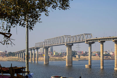 Bridge over river in city against clear sky