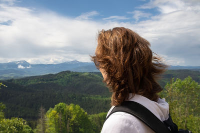 Rear view of woman looking at mountains against sky