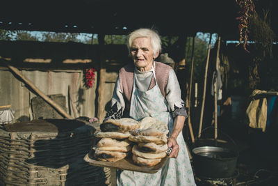 Portrait of a smiling young woman holding food outdoors