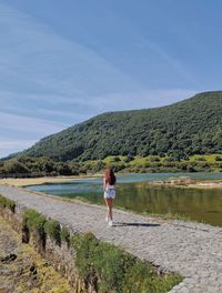 Rear view of woman standing on mountain against sky