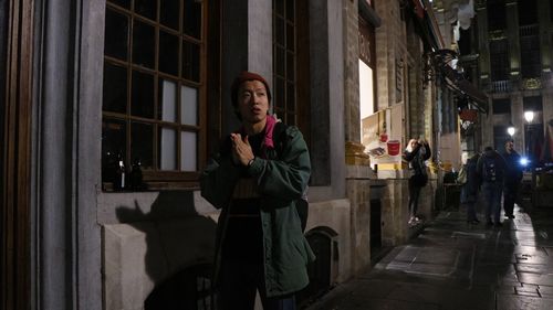 Young woman standing against illuminated building at night