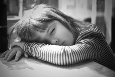 Close-up portrait of girl lying on table at home