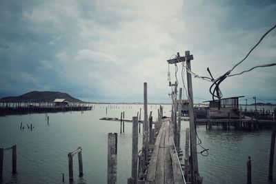 Sailboats on pier at harbor against sky