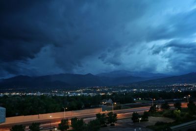 Illuminated cityscape against cloudy sky