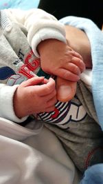 Midsection of mother and baby holding hands