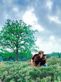 Couple sitting on field against sky