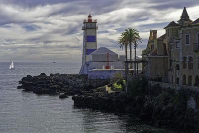 Lighthouse by sea against sky