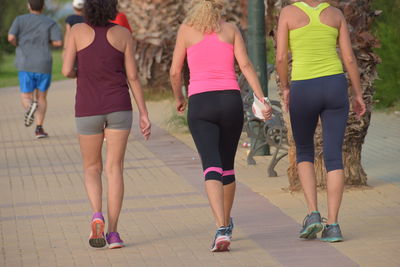 Rear view of three women running on footpath