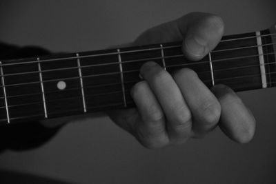 Close-up of hand playing guitar against wall
