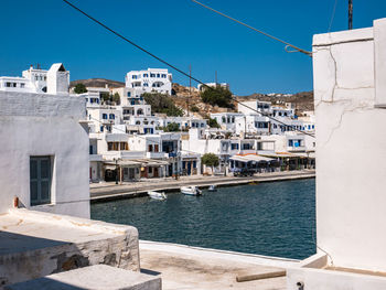 Sailboats in sea by buildings against clear blue sky