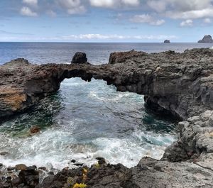 Scenic view of rocks on shore against sky