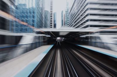 Blurred motion of railroad station amidst buildings in city